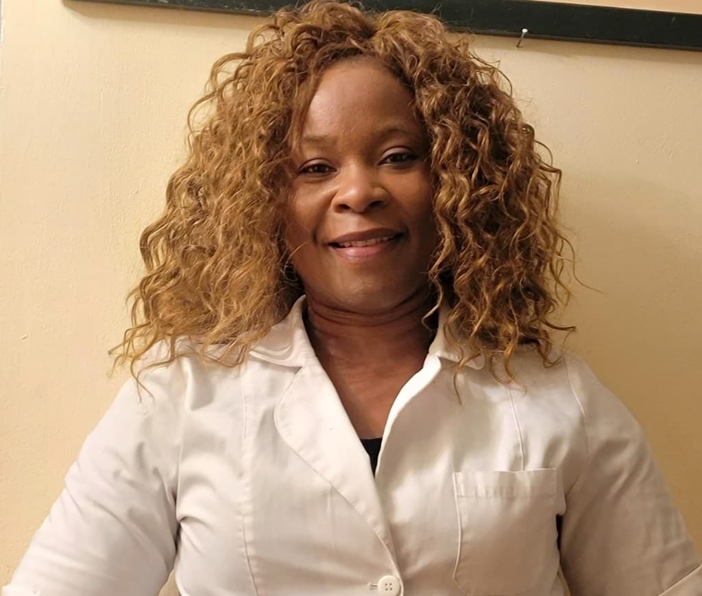 Portrait of Ntoge Penda in a white lab coat, smiling at the camera